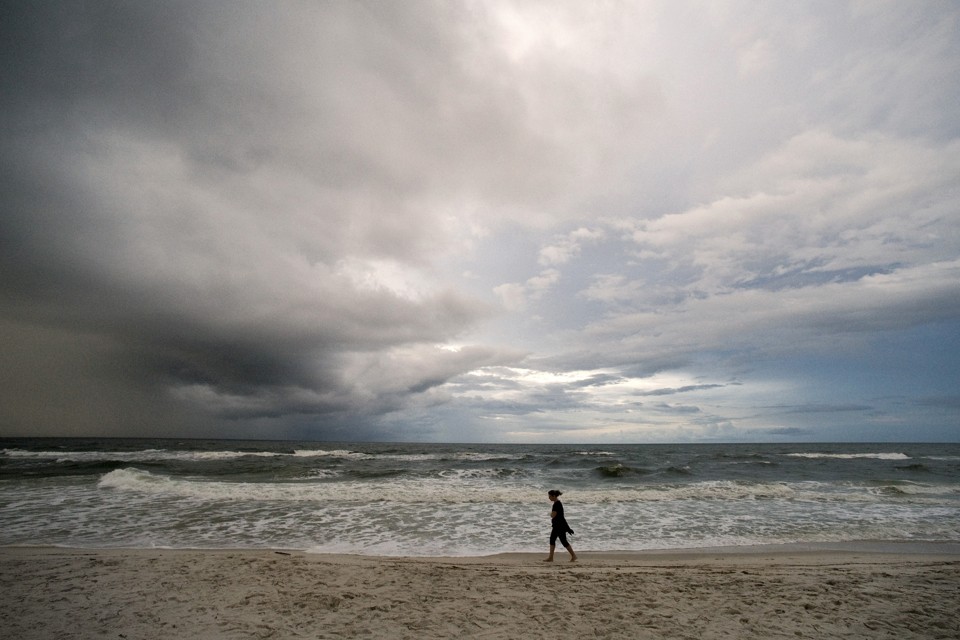 A beachgoer takes an early morning walk as storm clouds from a weakening Tropical Depression Karen approach Orange Beach